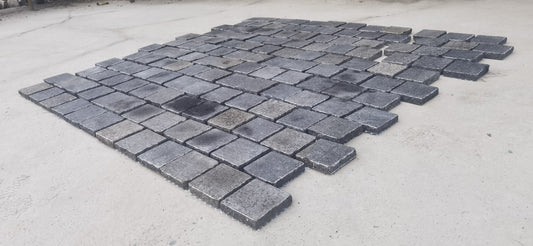 Black granite cobble stone from The Nurso, showing textured surface and irregular shape for durable outdoor paving.